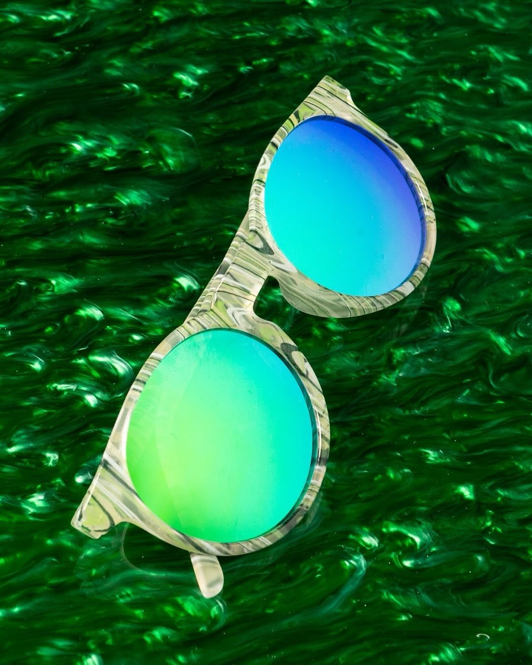Óculos de sol com lentes coloridas sobre fundo verde.