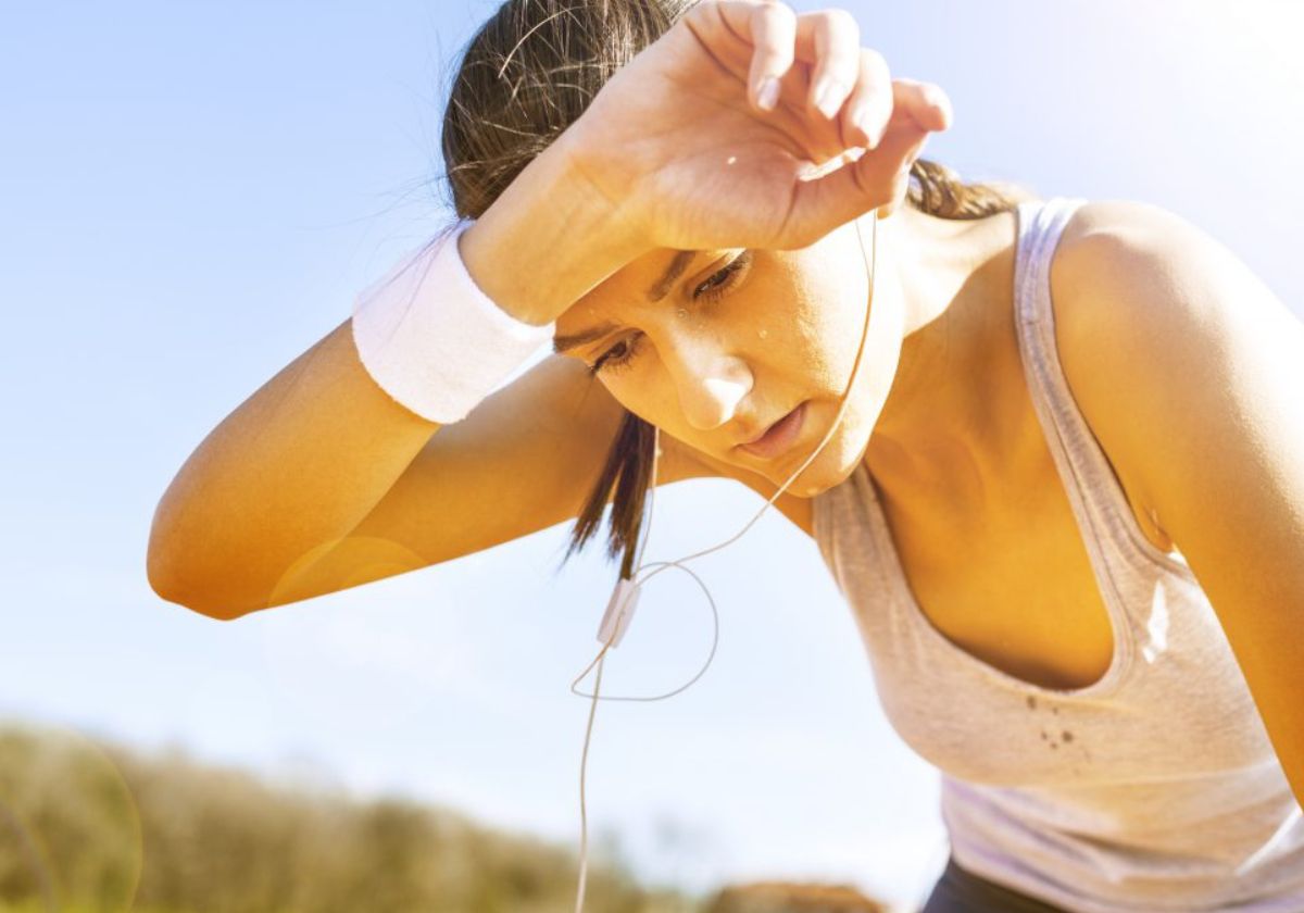 Mulher se exercitando sob o sol, parecendo cansada